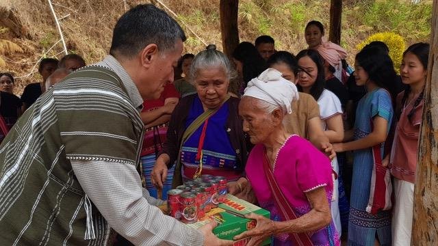 An elderly lady receiving food items from Jung 